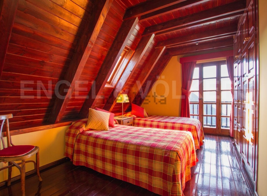 Cozy attic bedroom with twin beds, plaid bedding, and wooden beams.