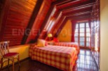Cozy attic bedroom with twin beds, plaid bedding, and wooden beams.
