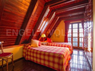 Cozy attic bedroom with twin beds, plaid bedding, and wooden beams.