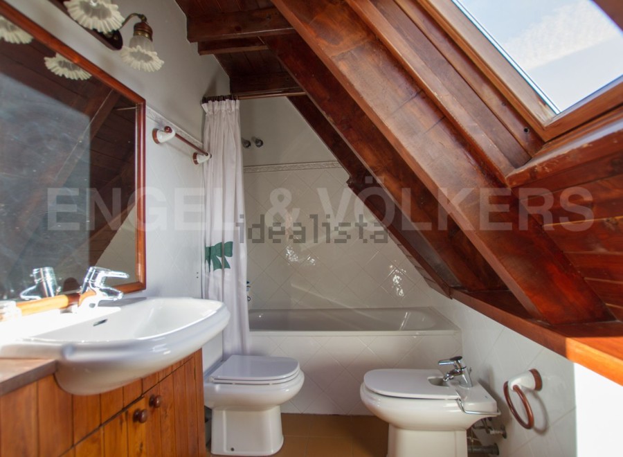 Charming attic bathroom with wooden beams, a bathtub, toilet, and bidet.