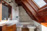Charming attic bathroom with wooden beams, a bathtub, toilet, and bidet.