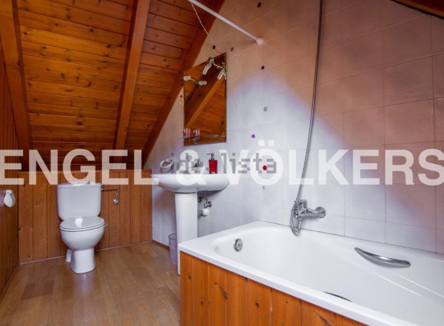 Charming attic bathroom with wooden finishes and a bathtub.