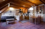 Cozy attic apartment with exposed wooden beams, open-plan kitchen and living area, and a small dining space.