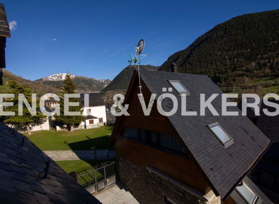 Mountain view home with slate roof and large windows.