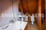 Charming attic bathroom with wooden beams, bathtub, toilet, and pedestal sink.