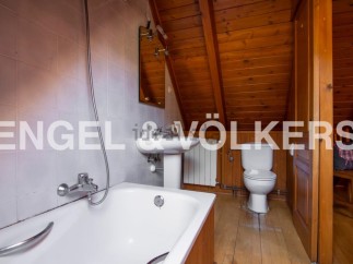Charming attic bathroom with wooden beams, bathtub, toilet, and pedestal sink.
