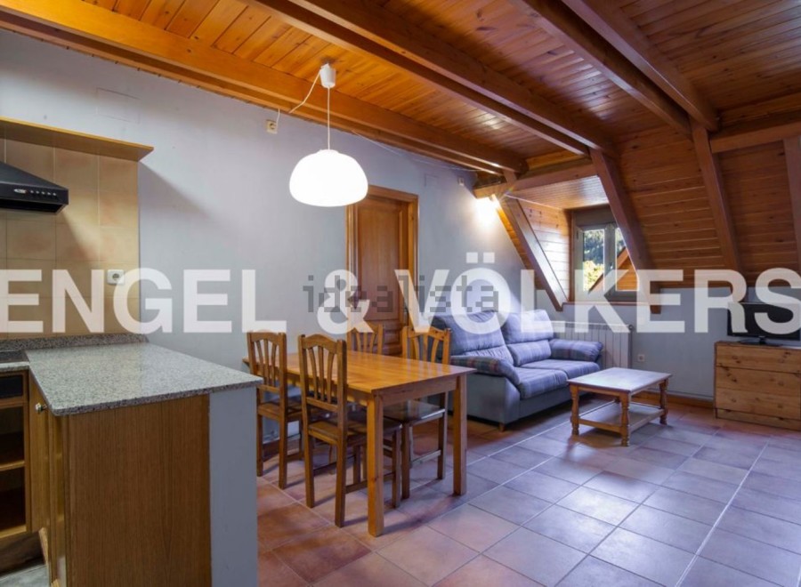 Cozy attic apartment with wooden beams and tiled floors.