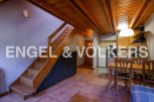 Cozy apartment featuring a wooden staircase, open kitchen with dining area, and terracotta tile floors.