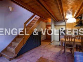 Cozy apartment featuring a wooden staircase, open kitchen with dining area, and terracotta tile floors.