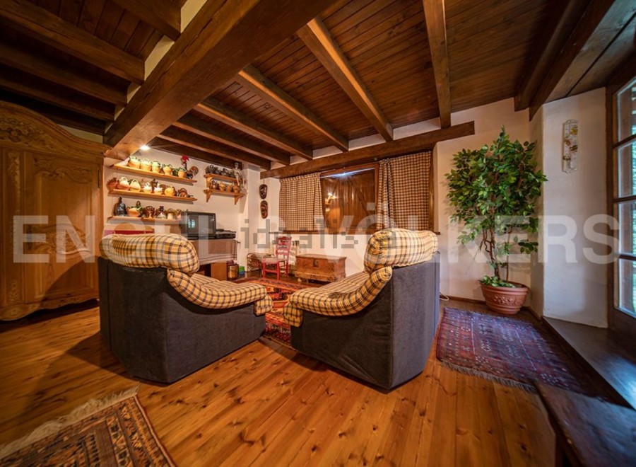 Cozy living room with wooden beams, hardwood floors, and comfortable armchairs.