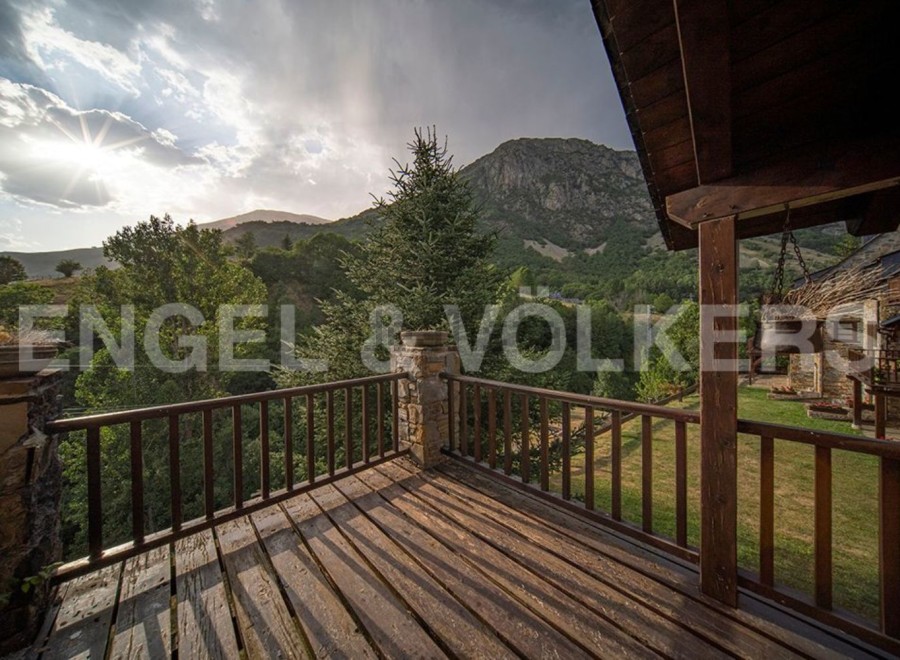 Mountain view balcony with wooden deck and railing.