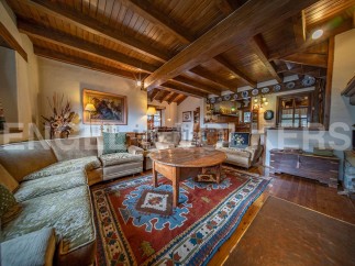 Rustic mountain chalet with exposed wooden beams and a cozy living area featuring a large, ornate rug and comfortable seating.