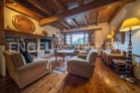 Rustic living room with wooden beams, stone fireplace, and large windows offering scenic views.