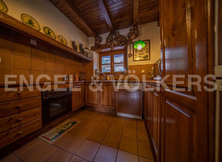 Rustic kitchen with wooden cabinets and terracotta tile floors.