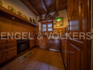 Rustic kitchen with wooden cabinets and terracotta tile floors.