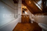 Charming attic bathroom with wooden beams, a bathtub, and a toilet.