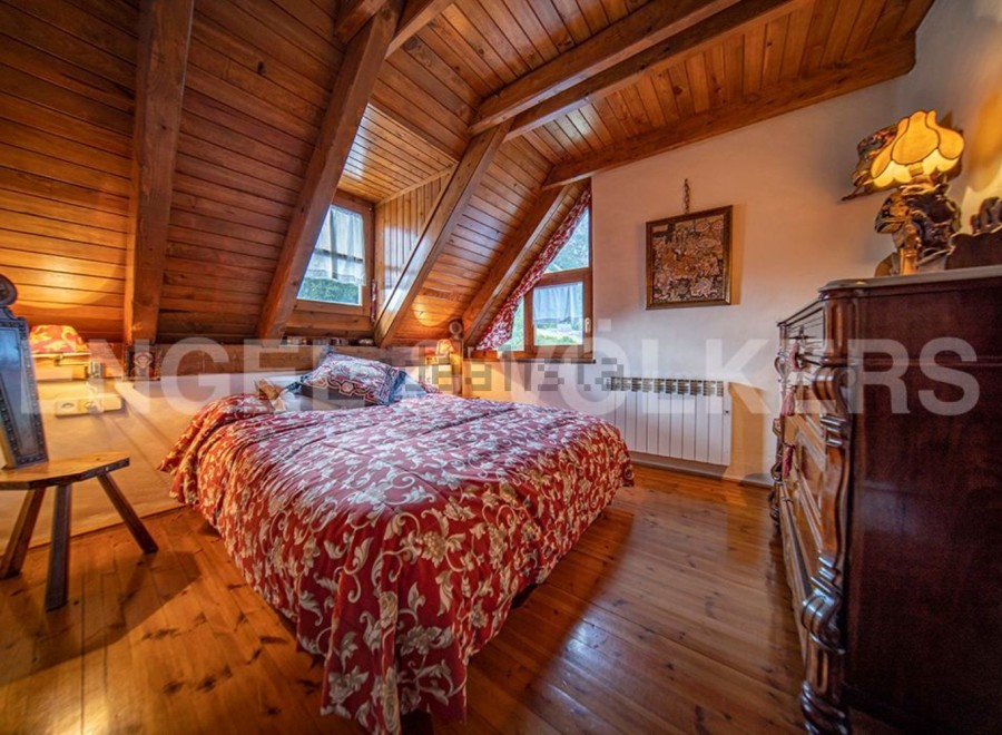 Cozy attic bedroom with wooden beams and hardwood floors.
