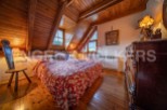 Cozy attic bedroom with wooden beams and hardwood floors.