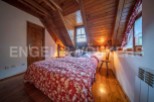 Cozy attic bedroom with wooden beams, floral bedding, and warm lighting.