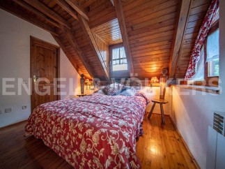 Cozy attic bedroom with wooden beams, floral bedding, and warm lighting.