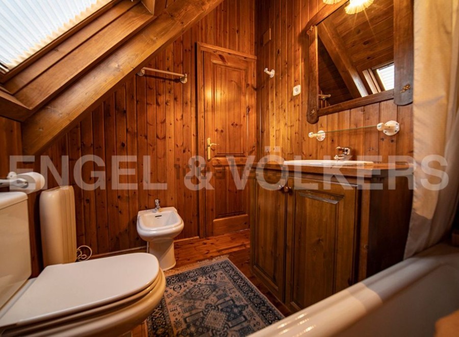 Charming wooden bathroom with a bathtub, toilet, bidet, and sink.