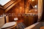 Charming wooden bathroom with a bathtub, toilet, bidet, and sink.