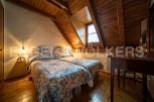Charming attic bedroom with twin beds, featuring a rustic wooden ceiling and walls.