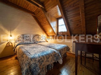 Charming attic bedroom with twin beds, featuring a rustic wooden ceiling and walls.