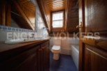 Charming attic bathroom with wooden beams, white tiled walls, and a wooden vanity.