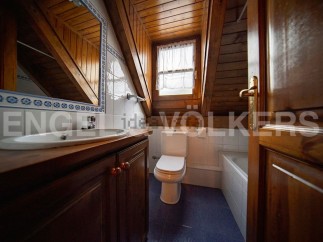 Charming attic bathroom with wooden beams, white tiled walls, and a wooden vanity.