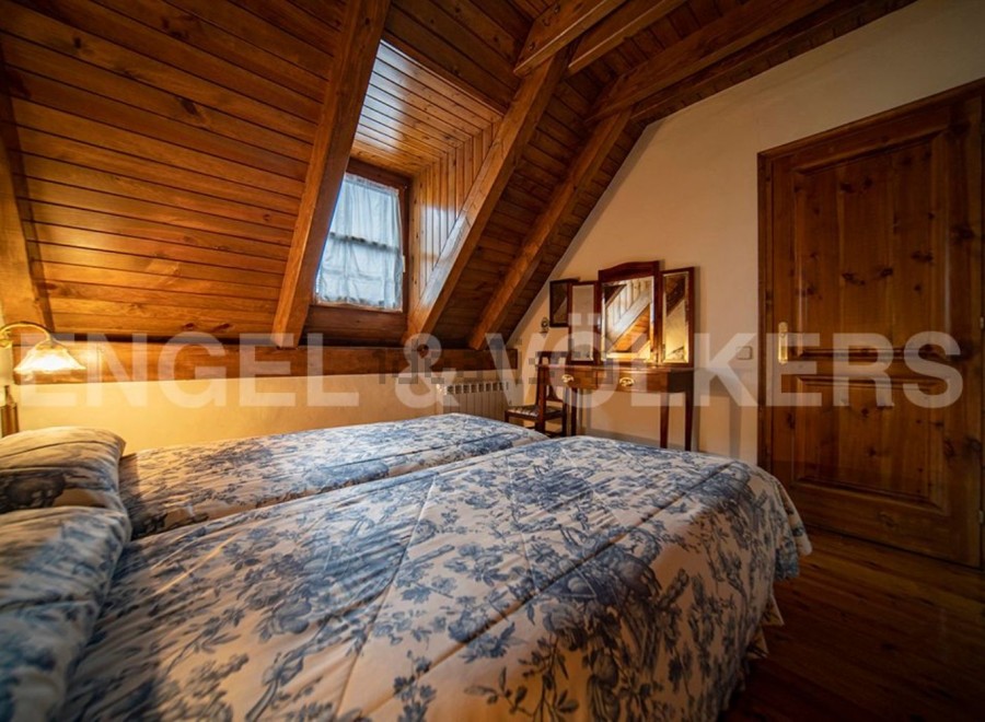 Cozy attic bedroom with twin beds, wooden beams, and a charming floral duvet.
