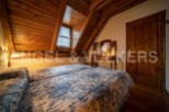 Cozy attic bedroom with twin beds, wooden beams, and a charming floral duvet.