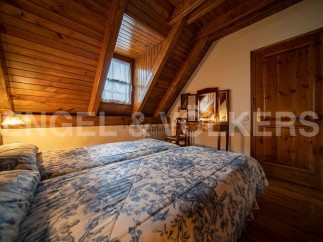 Cozy attic bedroom with twin beds, wooden beams, and a charming floral duvet.