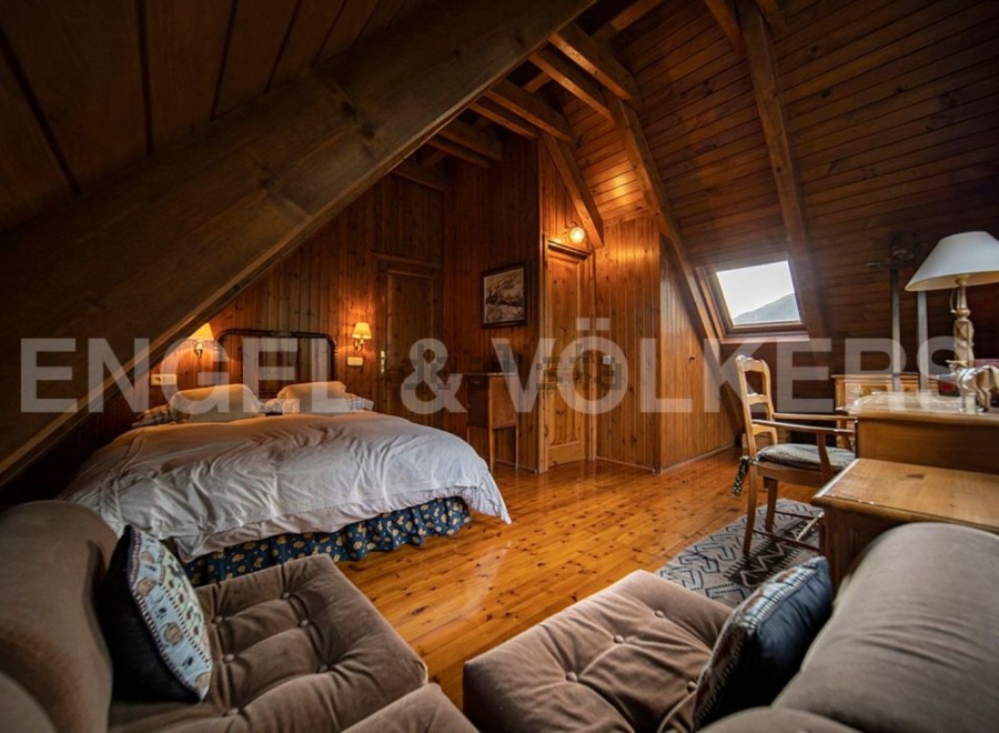 Cozy attic bedroom with wooden beams and hardwood floors.