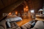 Cozy attic bedroom with wooden beams and hardwood floors.