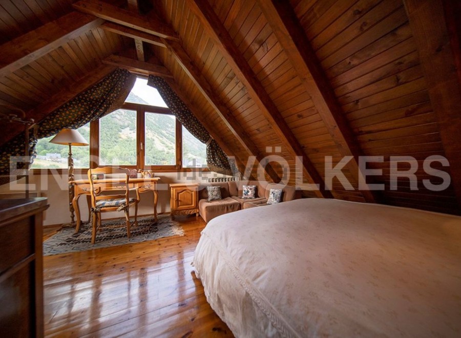 Cosy attic bedroom with wooden beams and mountain views.