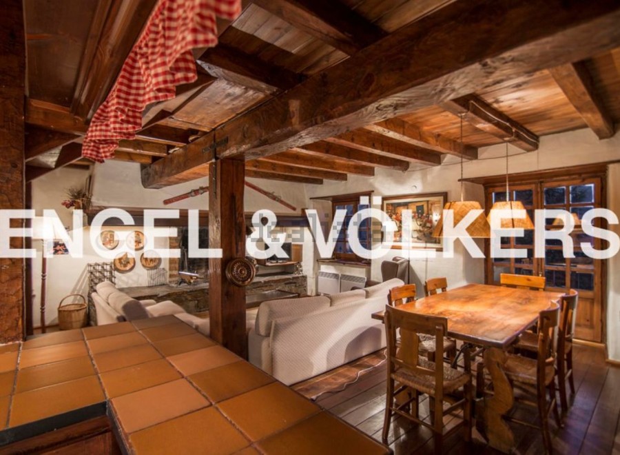 This stunning chalet boasts a spacious open-plan living area with exposed wooden beams and a cozy fireplace, perfect for relaxing after a day on the slopes.