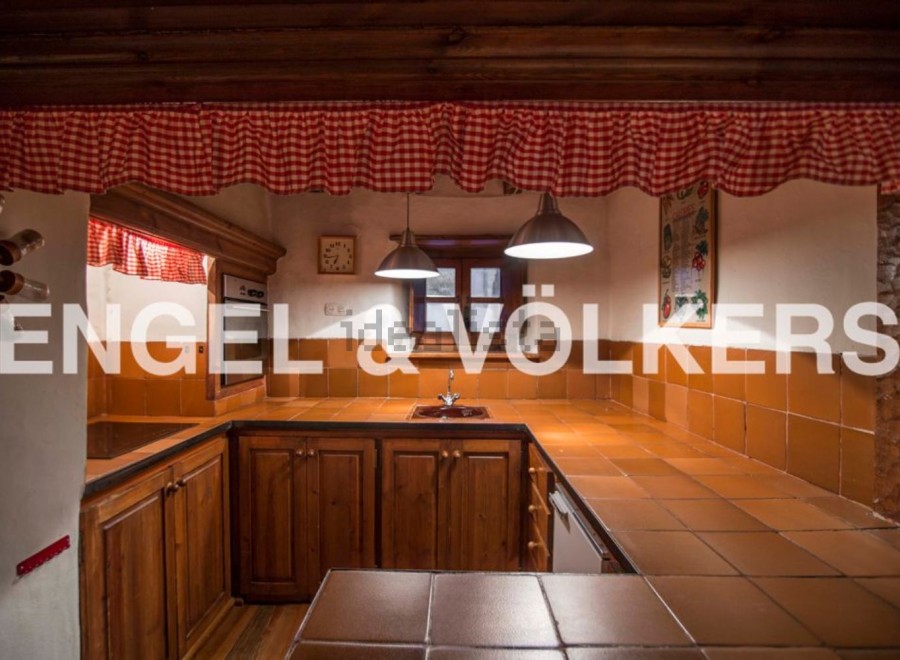 Rustic kitchen with wooden cabinets and terracotta tile countertops.