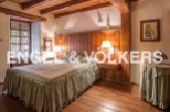 Rustic bedroom with wooden beams and floors, featuring a comfortable bed with a ruffled bedskirt and wooden headboard.
