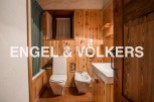Rustic bathroom with wooden walls and floors, featuring a toilet, bidet, bathtub, and sink.