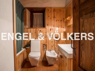 Rustic bathroom with wooden walls and floors, featuring a toilet, bidet, bathtub, and sink.