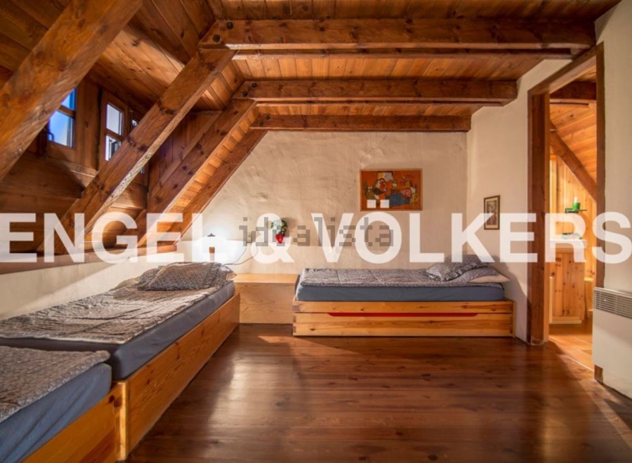 Charming attic bedroom with wooden beams and twin beds, offering a cozy and rustic atmosphere.