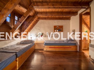 Charming attic bedroom with wooden beams and twin beds, offering a cozy and rustic atmosphere.