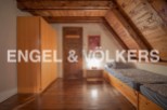 Charming attic room with wooden beams and floors, featuring built-in wardrobe and twin beds.