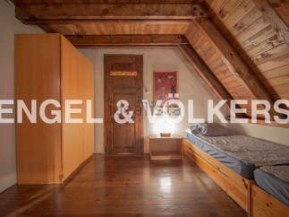 Charming attic room with wooden beams and floors, featuring built-in wardrobe and twin beds.