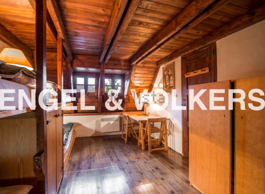 Charming attic room with wooden beams and floors, featuring built-in bunk beds and a small workspace.