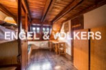 Charming attic room with wooden beams and floors, featuring built-in bunk beds and a small workspace.