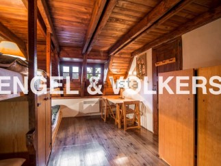 Charming attic room with wooden beams and floors, featuring built-in bunk beds and a small workspace.