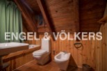 Rustic bathroom with wooden walls and ceiling, featuring a bathtub, toilet, bidet, and sink.