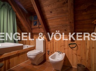 Rustic bathroom with wooden walls and ceiling, featuring a bathtub, toilet, bidet, and sink.
